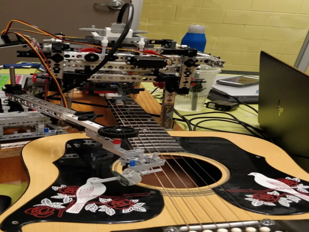 Guitar-playing robot assembled over an acoustic guitar